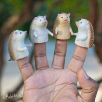 Four Hedgehog finger puppets on a hand with trees in the background