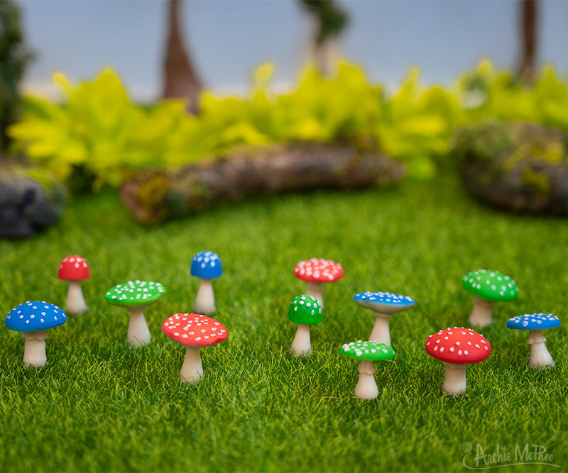 Twelve red, green and blue itty bitty mushrooms on a miniature lawn 
