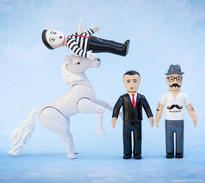 Toy unicorn piercing a mime with its horn while other action figures watch
