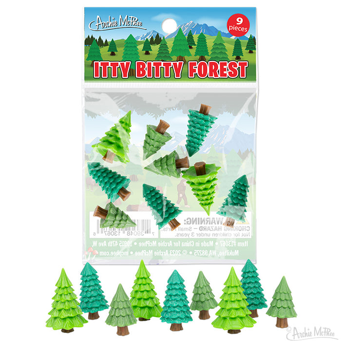 Itty Bitty Forest toy set featuring 9 miniature vinyl trees in various shades of green, packaged in a clear bag with colorful product label showing mountain scenery. Tiny trees displayed below package.