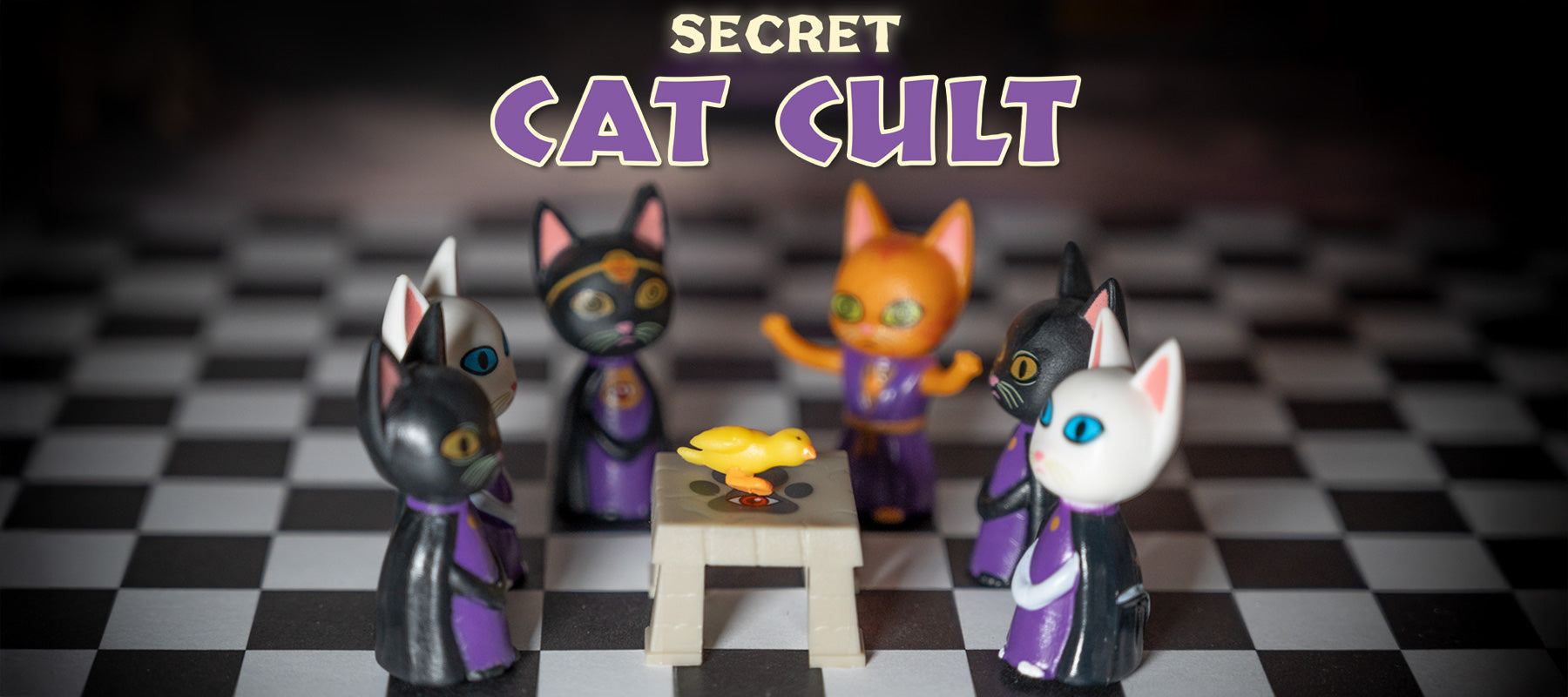 Vinyl cats in robes are seated around a table with a rubber duck. Above them, the text reads "Secret Cat Cult," suggesting their mysterious feline society.