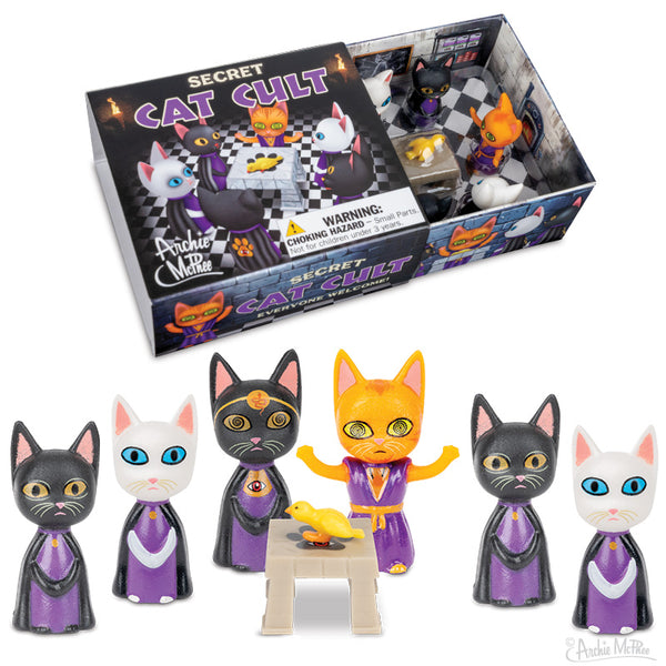 Six toy cat figurines dressed in cult robes surrounding an altar with a bird on it with a matchbox style package in the background.