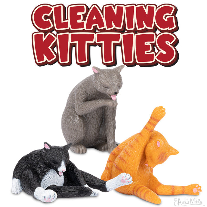 Playful vinyl figurines of cats in various cleaning poses, including grey, black and white, and orange cats, under bold red text "Cleaning Kitties