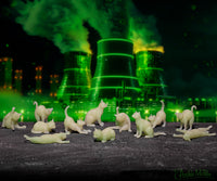 Tiny glow-in-the-dark cat figurines scattered on dark surface with glowing green nuclear power plant cooling towers in background, creating eerie atmosphere