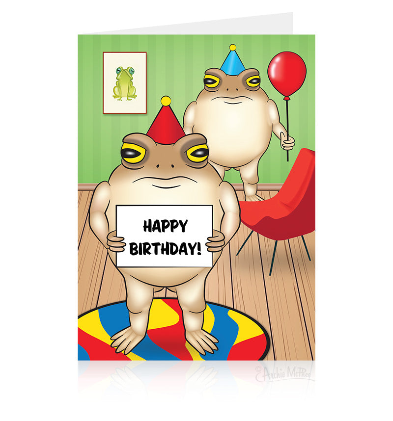 A greeting card depicting two illustrated grumpy frogs wearing party hats in a festive room, one holding and red balloon and the other holding a sign with the words "Happy Birthday!"