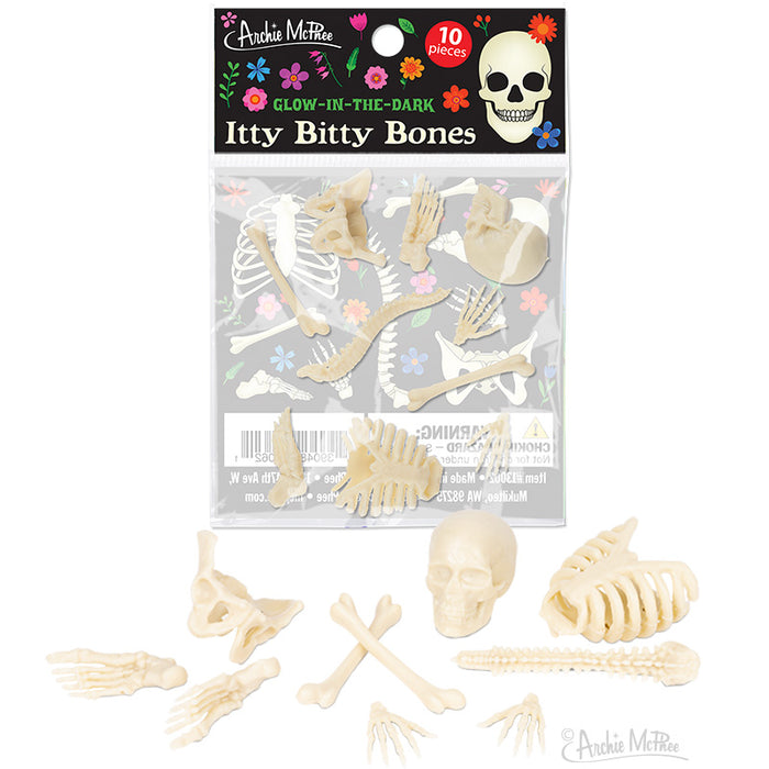 Glow-in-the-dark miniature bone replicas for Halloween decor, displayed in packaging with colorful floral design and skull illustration. Various bone shapes visible, including skull, ribcage, and hand bones, arranged on white background.