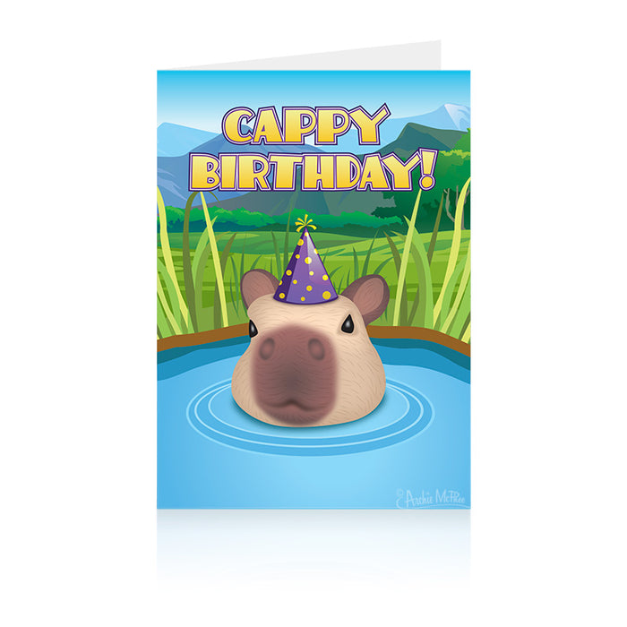 Capybara birthday greeting card featuring a capybara wearing a purple party hat, emerging from blue water surrounded by grass and mountains, with colorful text saying "Cappy Birthday!