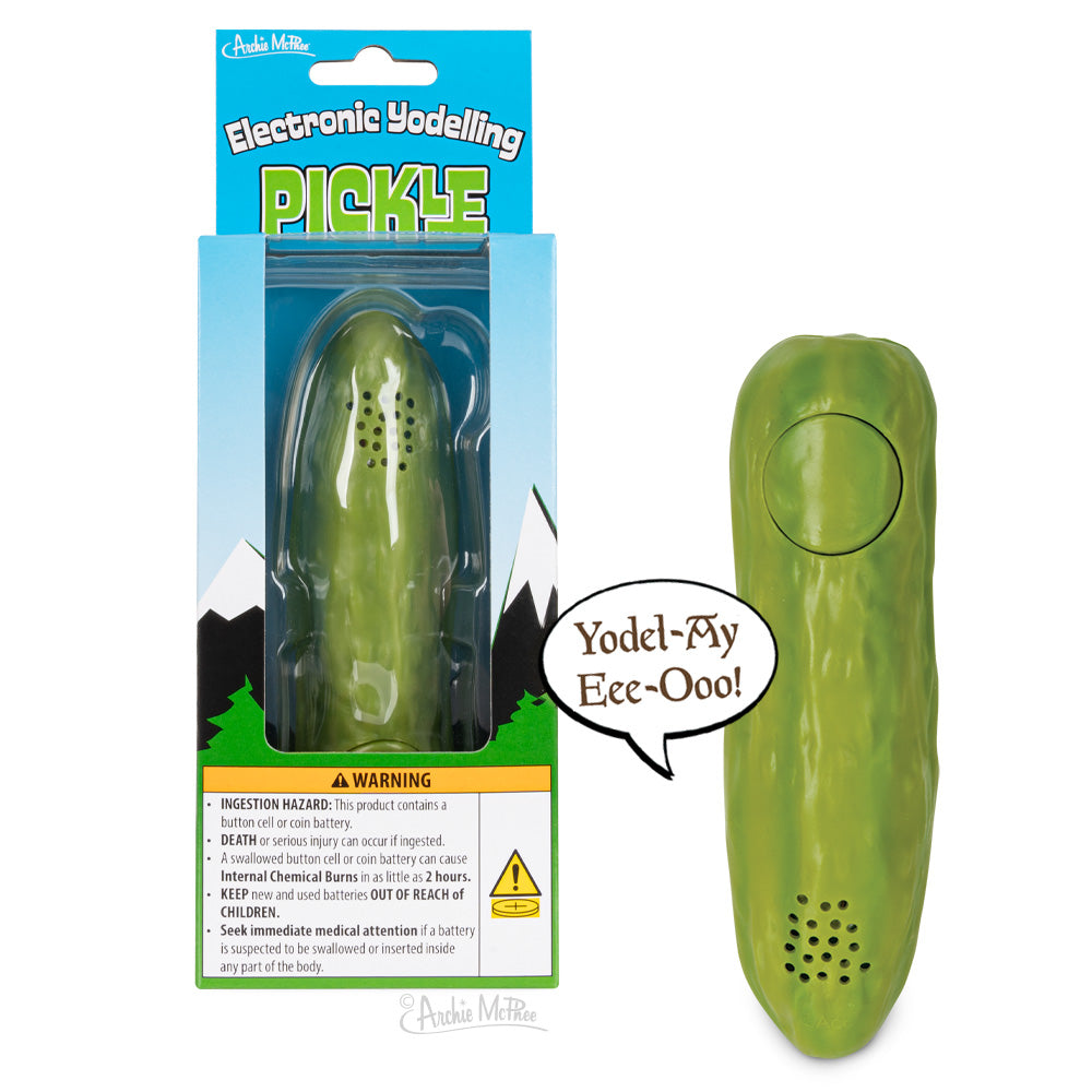 Electronic Yodelling Pickle novelty toy in packaging and standalone, featuring green pickle-shaped device with button and speech bubble saying "Yodel-Ay-Eee-Ooo!". Product box displays mountain scenery and warning labels.