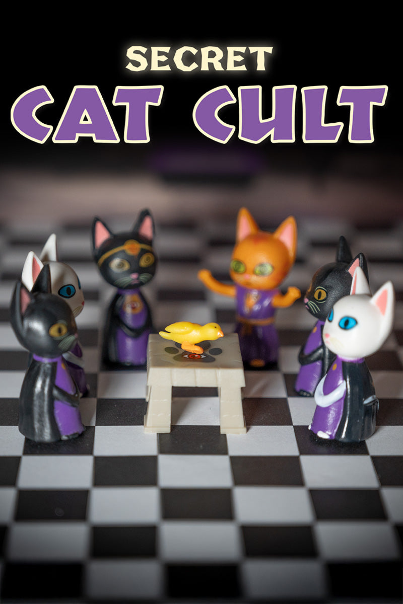 Vinyl cats in robes are seated around a table with a rubber duck. Above them, the text reads "Secret Cat Cult," suggesting their mysterious feline society.