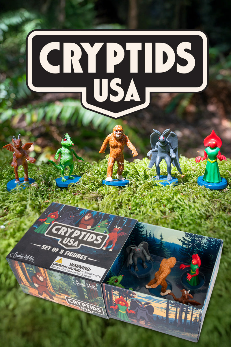 Five cryptid figurines stand on moss under a Cryptids USA sign with a matchbox-style box in the foreground.