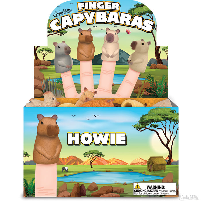 Finger Capybaras display box featuring four colorful capybara puppets on fingers, set against a vibrant savanna backdrop with trees, water, and wildlife. Product name and warning label visible on the packaging.