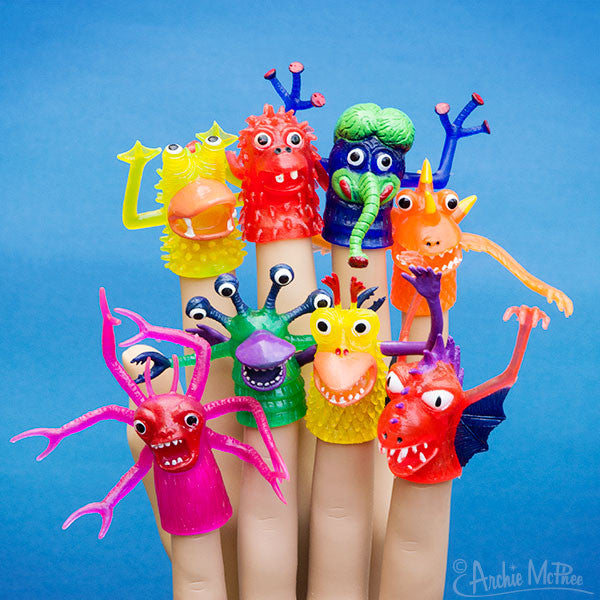 Colorful assortment of whimsical finger monsters with bulging eyes and exaggerated features, displayed on fingertips against a vibrant blue background. Variety of shapes, sizes, and expressions showcasing the product's playful and quirky nature.