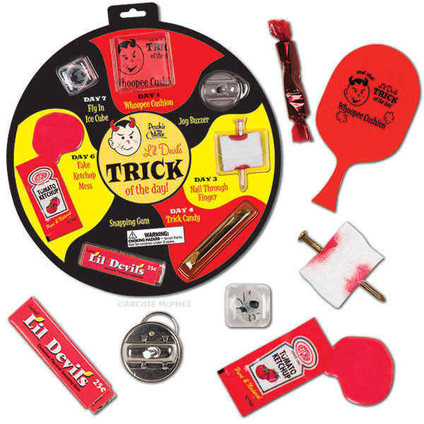 Li'l Devil's Trick of the Day prank collection featuring seven classic joke items including whoopee cushion, joy buzzer, nail through finger, trick candy, snapping gum, fake ketchup, and fly in ice cube, displayed on a circular card with individual items scattered around