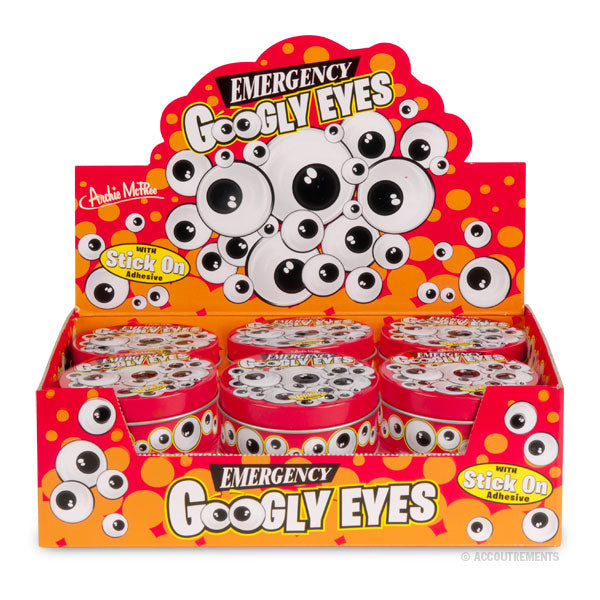 Bulk display box of Emergency Googly Eyes, featuring multiple tins with googly eye designs. Bright red and orange packaging with playful eye graphics, perfect for parties and crafts.