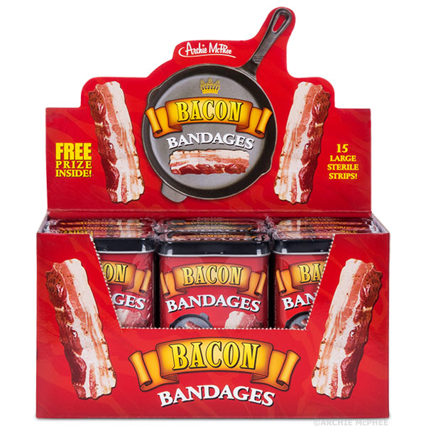 Display box of Bacon Bandages tins, featuring red packaging with bacon strip graphics. Box contains multiple tins, highlighting "15 Large Sterile Strips" and "Free Prize Inside!" Ideal for bulk purchase of novelty bandages.