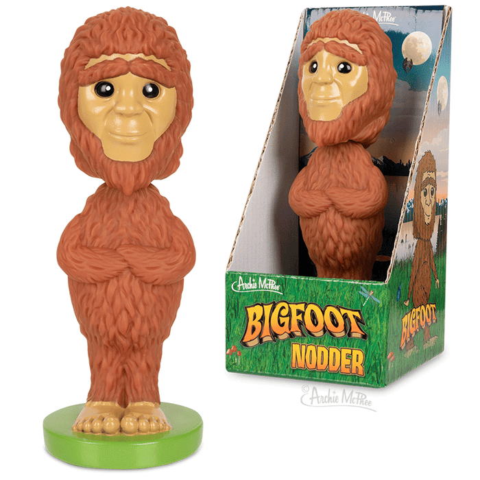 Bigfoot Nodder figurine with brown fur and friendly face, standing on green base. Shown both out of box and in colorful packaging featuring woodland scene and product name.