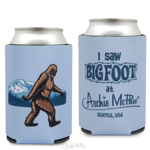 Bigfoot can cooler set featuring two designs: one with a walking Bigfoot silhouette against a mountain backdrop, and another with "I saw Bigfoot at Archie McPhee Seattle, USA" text, both on light blue foam koozies for beverages.