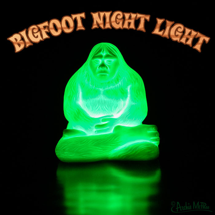 Glowing green Bigfoot night light in meditation pose, illuminated against dark background with product name in orange text above