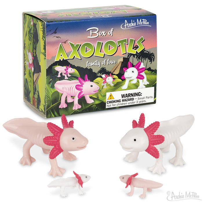 Box of Axolotls toy set featuring four cute vinyl figurines, two large and two small, in light pink and white colors. Product box displays tropical scene with colorful axolotl illustrations. Warning label visible for choking hazard.