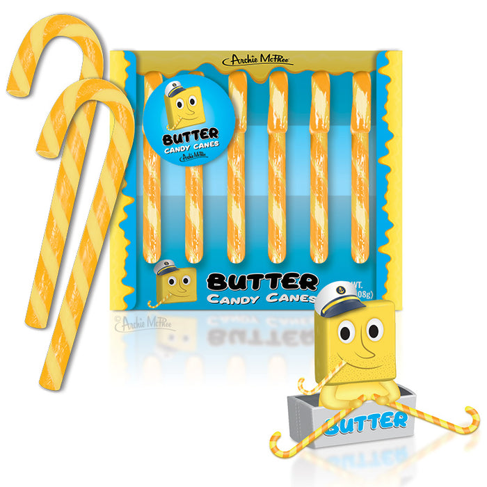 Yellow and white striped butter-flavored candy canes in packaging, with cartoon butter character mascot. Six candy canes visible in box, two larger canes displayed outside. Festive holiday treat with unique butter flavor concept.