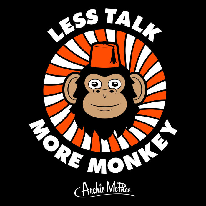 Cartoon monkey wearing red fez centered in orange and white swirl background with text "Less Talk More Monkey" and Archie McPhee logo on black t-shirt