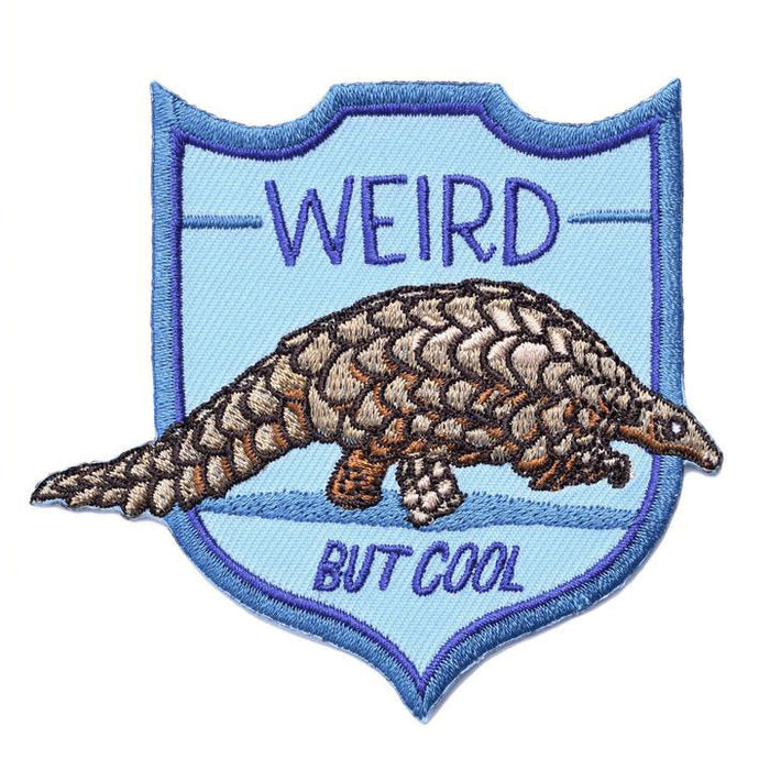 Embroidered patch featuring a detailed pangolin on a light blue shield-shaped background with 'WEIRD' above and 'BUT COOL' below in dark blue text, bordered by a navy blue outline