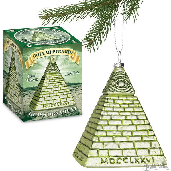 Dollar Pyramid glass ornament resembling the iconic symbol from US currency, featuring a green pyramid with all-seeing eye design, hanging from a silver chain next to its product box and pine branch