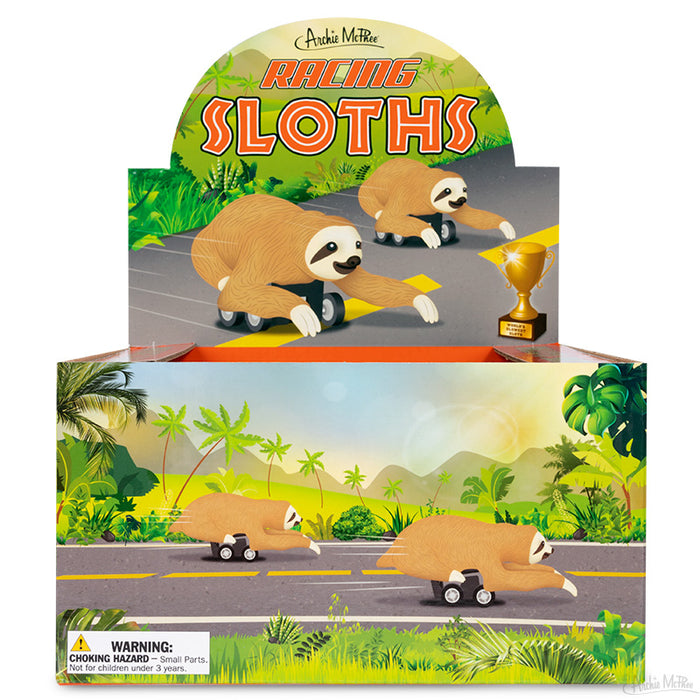 Colorful display box featuring Racing Sloths toy set, showing cartoon sloths on a racetrack with tropical background. Includes product warning and Archie McPhee branding.