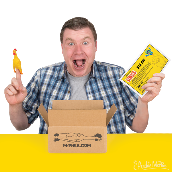 Excited man in plaid shirt holding rubber chicken finger puppet and yellow gift card, with Archie McPhee box containing quirky items on yellow background, representing the Archie McPhee Starter Kit for unique gift-giving