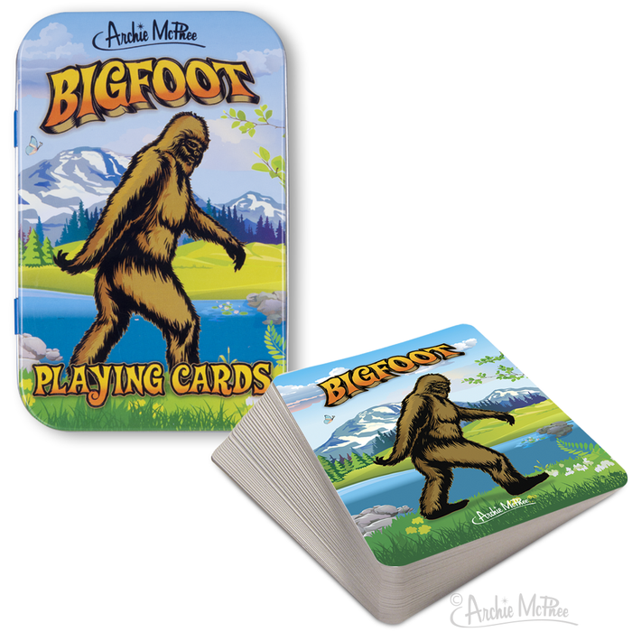 Bigfoot playing cards in decorative outdoor-themed tin box, featuring Bigfoot illustration on card backs. Scenic mountain landscape with lake in background. Perfect for camping and outdoor enthusiasts.