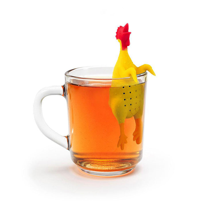 Whimsical yellow rubber chicken tea infuser floating in a clear glass mug filled with amber-colored tea, showcasing its unique design and perforated body for steeping