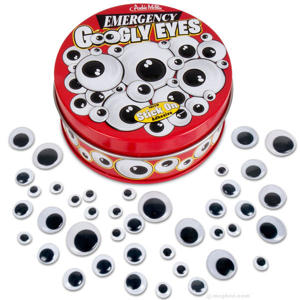 Red circular tin of Emergency Googly Eyes with various sizes of adhesive plastic eyes scattered around, featuring a playful design of googly eyes on the lid