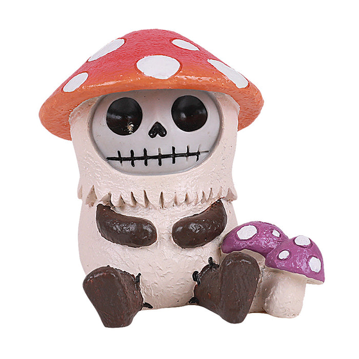 Cute skeleton figurine wearing a red and white spotted mushroom cap, sitting next to a smaller purple mushroom. The skeleton has large eyes, stitched mouth, and is dressed in a pale mushroom-shaped body with dark arms and legs.