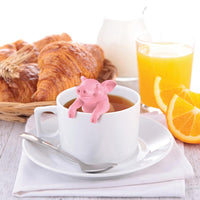 Hot belly tea infuser in a tea cup scene with croissants and a glass of orange juice