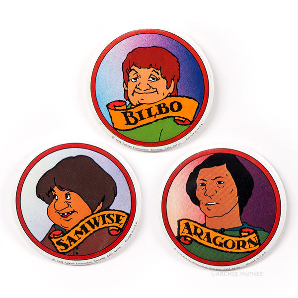 Vintage Lord of the Rings character pins featuring Bilbo, Samwise, and Aragorn from the 1978 animated movie. Colorful circular metal pins with character illustrations and names on banners.