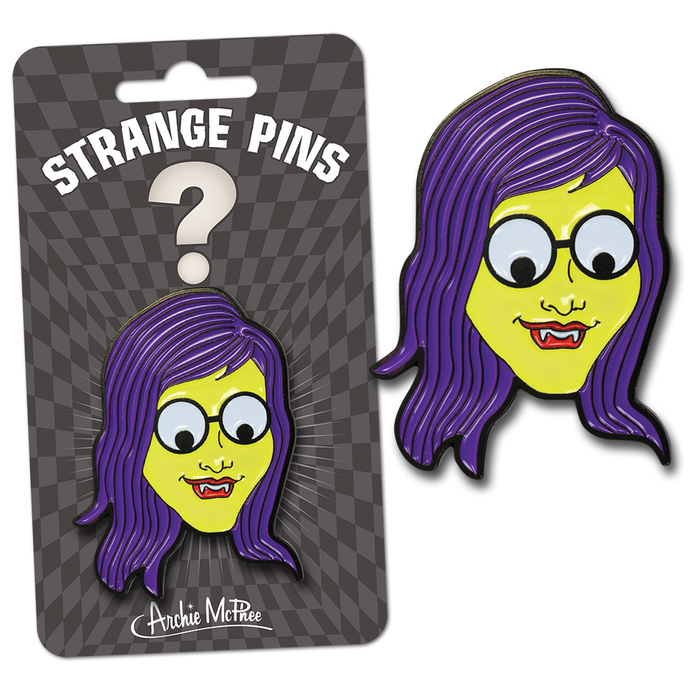 Monster Girl enamel pin with yellow face, purple hair, googly eyes, and vampire fangs, shown in packaging and as standalone pin. Part of Strange Pins collection by Archie McPhee.