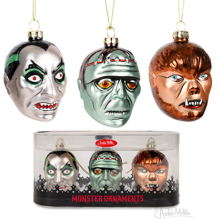 Set of three hand-blown glass monster ornaments featuring a vampire, Frankenstein's monster, and werewolf. Each ornament depicts a detailed, colorful monster face. Displayed in a clear plastic container labeled "Monster Ornaments" for festive Halloween or horror-themed Christmas decor.