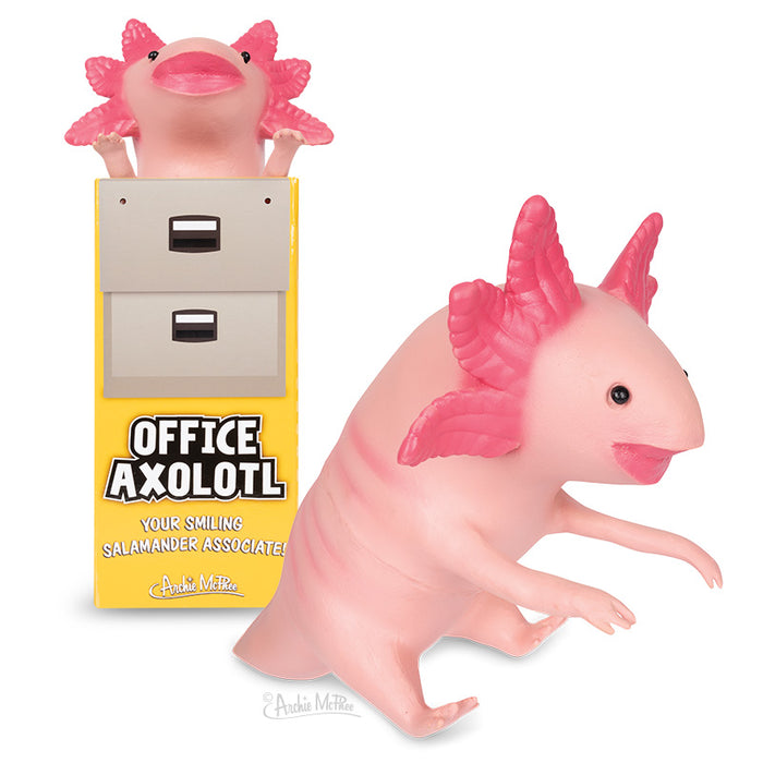 Pink Office Axolotl toy with poseable arms, smiling face, and frilly gills, shown next to product packaging featuring a yellow box and filing cabinet design. Cheerful desk companion for workspace mood boost.