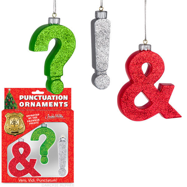 Glittery punctuation mark ornaments - green question mark, silver exclamation point, and red ampersand - hanging above product packaging for Punctuation Ornaments, featuring a festive design and humorous Latin phrase