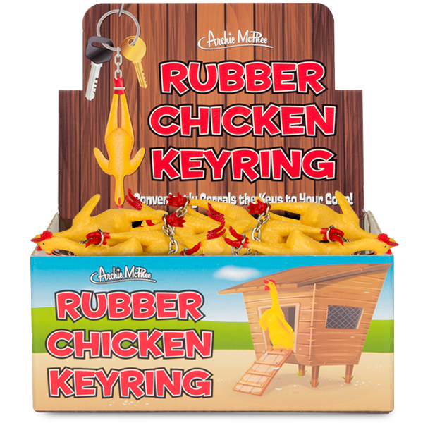 Display box filled with yellow rubber chicken keyrings, featuring a wooden background and colorful packaging. One keyring hangs on display above the box, showcasing the product's design.