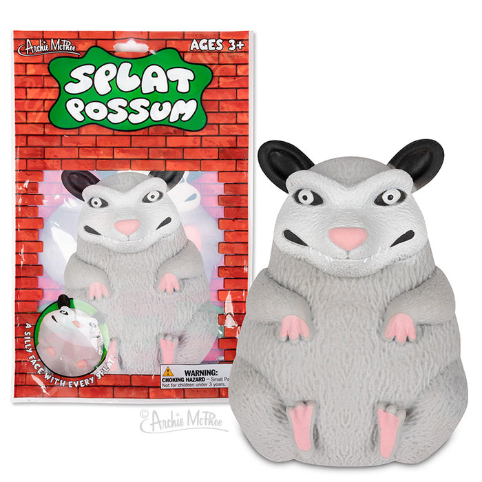 Splat Possum toy product image showing a gray plush possum with wide eyes and pink paws, packaged in a colorful box with brick background. The toy is designed for ages 3 and up and can be thrown or squished for stress relief.