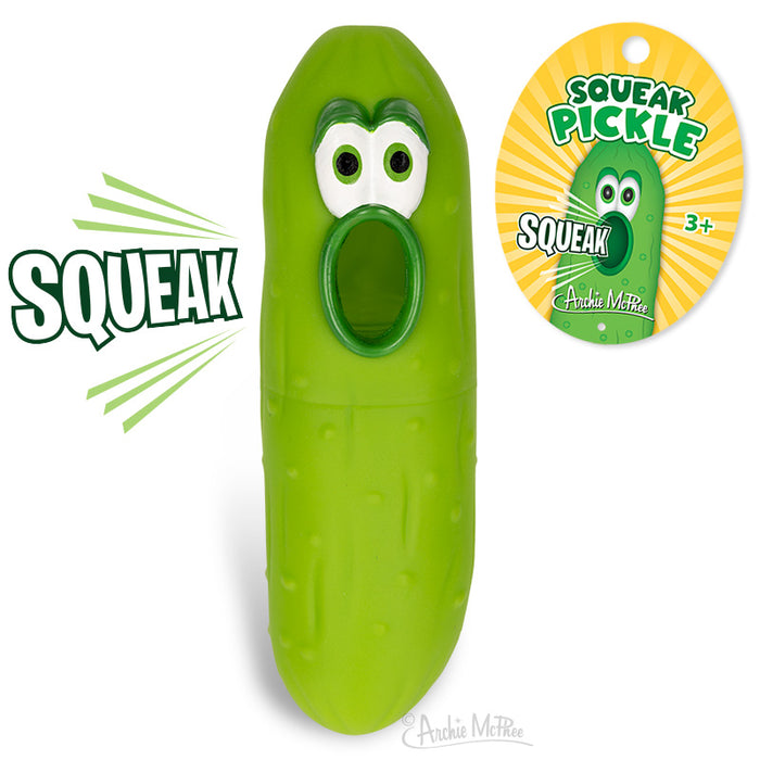 Squeaking green pickle toy with comical face and open mouth, next to product packaging featuring "Squeak Pickle" branding and cartoon pickle image. Novelty item for ages 3 and up by Archie McPhee.