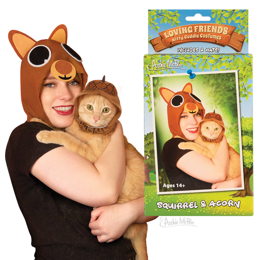 A woman in a squirrel hat holding an orange cat in an acorn hat with the product box next to them